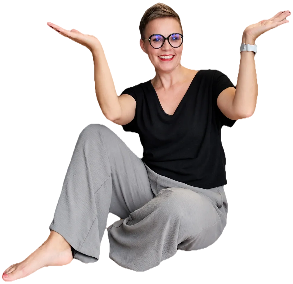 Marzena siedzi na podłodze i z uśmiechem rozkłada ręce
