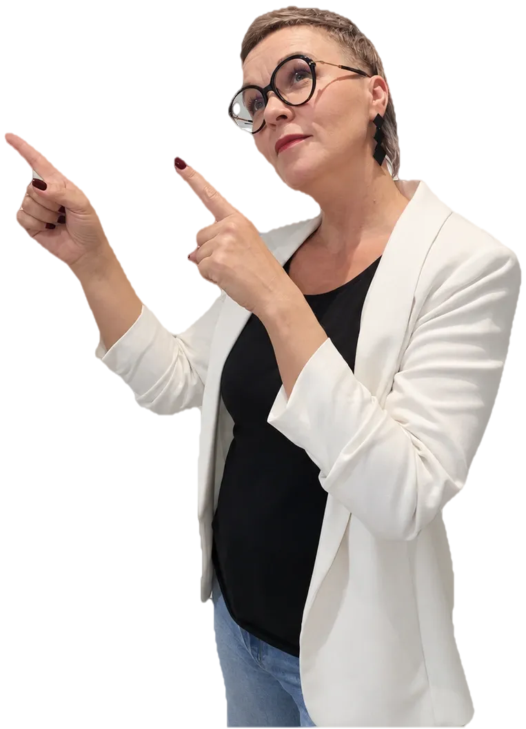 Marzena w białej marynarce wskazuje palcami w górę, na szafki